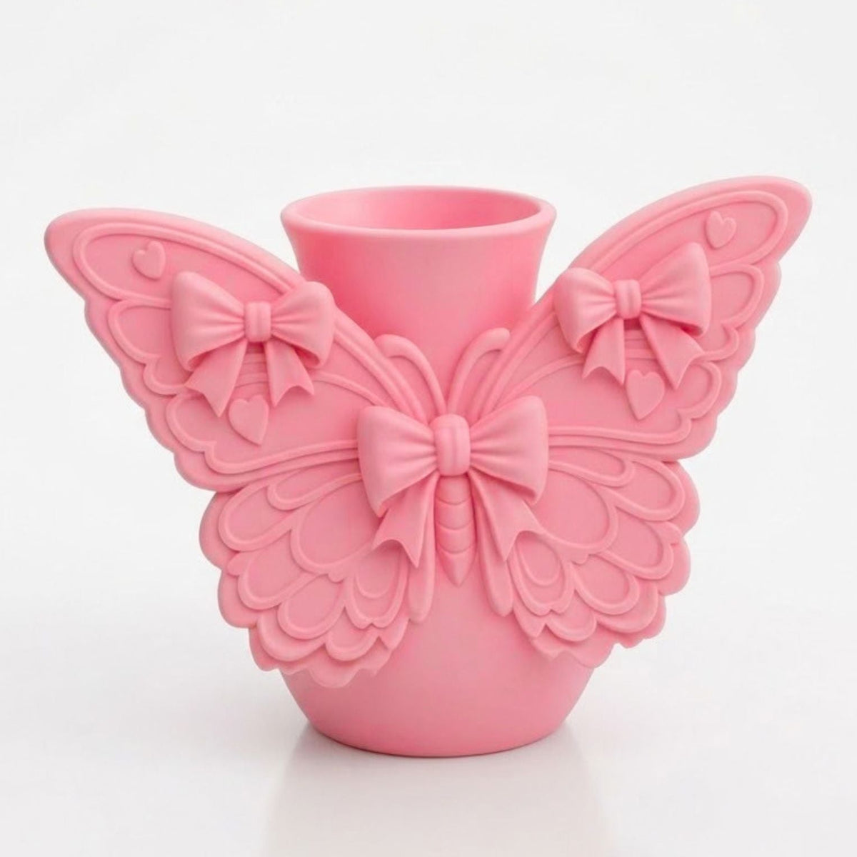 A pink ceramic vase shaped like a butterfly with wings and a central bow, set against a plain white background.